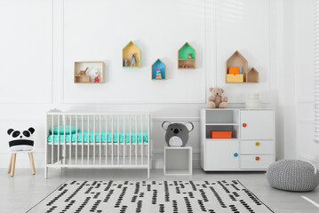 Comfortable crib near wall with color shelves in baby room. Interior design