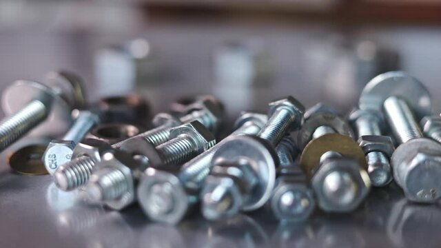 Slider shot video of metal chrome bolts and nuts in a chaotic order. Background concept for fasteners and construction topics. Repair and spare parts concept