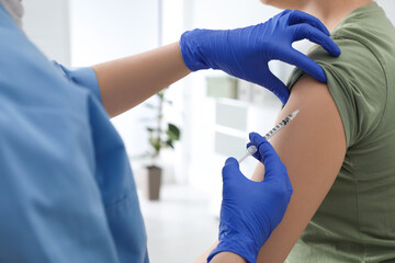 Obraz premium Doctor giving injection to woman in hospital, closeup. Immunization concept