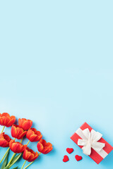 Mother's day background. Top view of gift with red tulip bouquet on blue table background