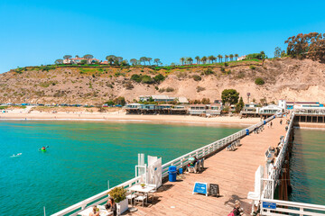 Top photo of a pier on Malibu Beach, California. People walking on the weekend. Los Angeles, USA -...