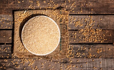 Top View of Cracked Wheat or Dalia in a Plate on Burlap Fabric Isolated on Wooden Background with Copy Space