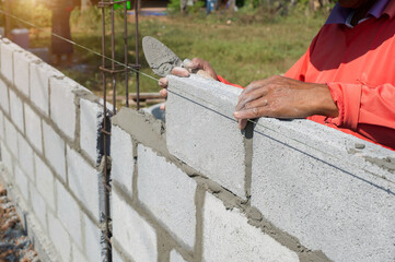 masonry worker make concrete wall by cement block and plaster at construction site