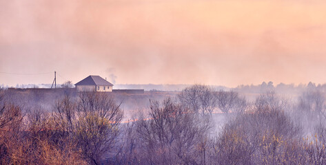 Dry grass burns on fields . Clouds of colorful smoke fly across the sky.