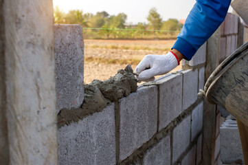 masonry worker make concrete wall by cement block and plaster at construction site