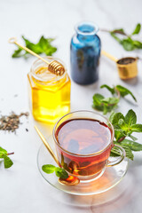 Black tea in glass transparent mug with mint leaves and honey. Calming and revitalizing tea, anti-stress and relaxation