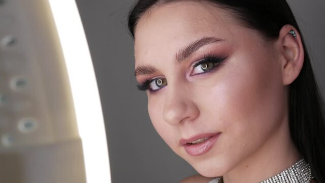 Portrait of a beautiful young girl model in stylish evening make up smoky eyes looks at the camera and posing. Eyes close up view. Long eyelash extensions and eye makeup in soft pink tones