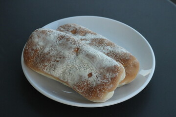 Close up ciabatta panini bread with flour on white plate