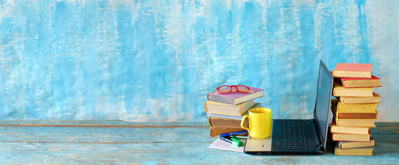 Stack of books and laptop computer,home office, homeschooling,reading,education, business concept. Free copy space, panoramic