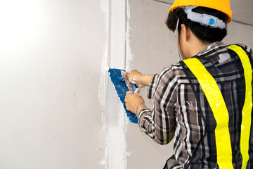 Construction worker plastering gypsum board or plasterboard panels wall with trowel. Home interior...