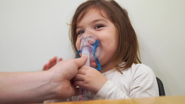 Toddler girl with oxygen nebuliser treatment at home. Inhaler therapy of bronchitis and lung disease. Asthmatic and allergy treatment. 