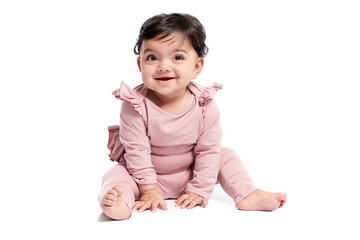 Cute female baby in lovely pink outfit smiling with mouth open. Attractive little baby sitting on floor and posing, isolated on white studio background. Concept of childhood.