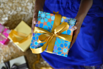 Close up of a kid's hand holding beautiful gift box, shot from above angle.
