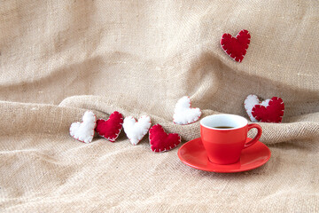 赤いコーヒーカップのコーヒーとたくさんのハートのデザイン（麻布の背景）	
