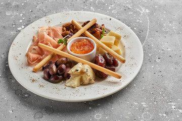 Set of snacks for wine. Prosciutto, parmesan, gorgonzola, almonds, olives, bread chips, mostard fruit confiture on gray marble background