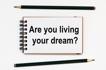WHITE SPIRAL NOTEBOOK, TWO PENCILS WITH TEXT Are you living your dream