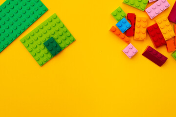 Kids toy constructor details scattered on yellow background