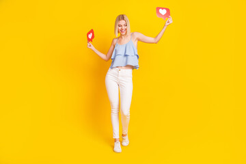 Full body photo of excited blond hair lady hold likes wear top pants isolated on yellow background