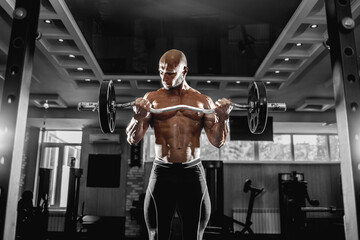 Muscular man working out in gym doing exercises with dumbbells at biceps, strong male naked torso abs