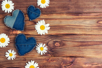 Obraz premium Daisies with denim hearts on wooden background.