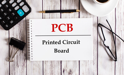 PCB Printed Circuit Board is written in a white notepad near a calculator, coffee, glasses and a...