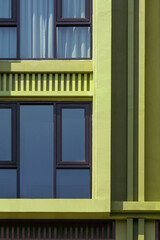 Obraz na płótnie Canvas Sunlight on glass windows surface of green modern building in vertical frame