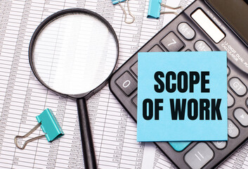 On the table are reports, a magnifying glass, a calculator, and a blue note sticker with the words...