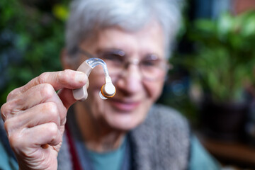 smiling elderly woman holding a hearing aid