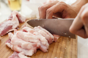 A man cook cuts pork meat with a knife. Cooking Concept