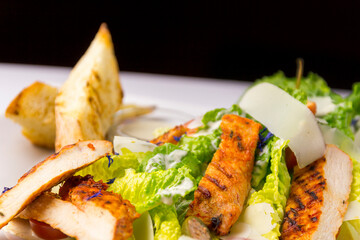 Salad with grilled chicken, black background