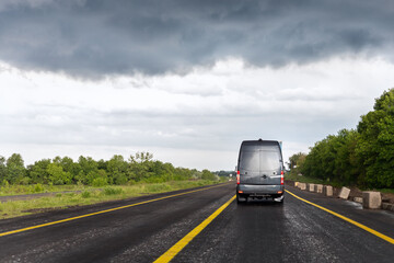 Back of delivery small shipment cargo courier van moving fast on wet highway road to city urban...