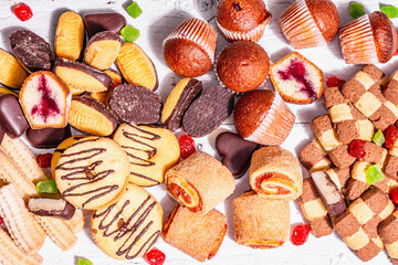 Assorted various cookies and cupcakes scattered on wooden boards background