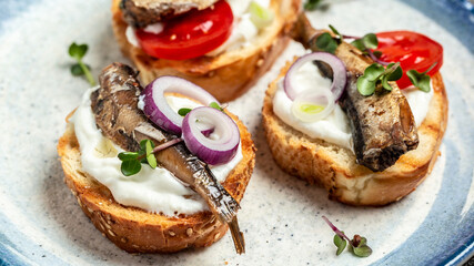 Sandwich smorrebrod with sprats, tomatoes and cream cheese. Food recipe background. Close up