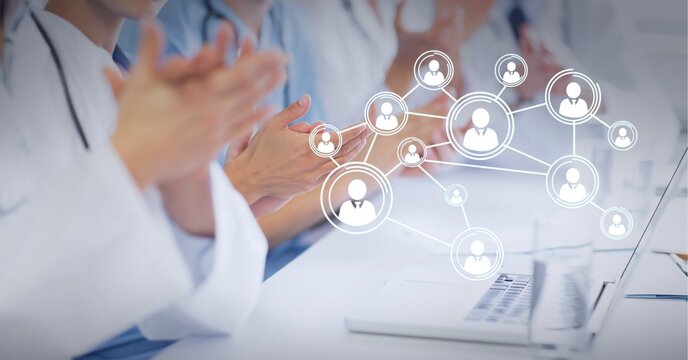 Connected network of bubbles with people icons over medical workers sitting at table