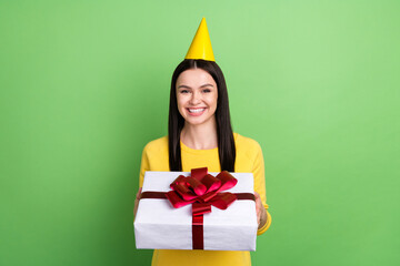 Photo portrait of woman wearing birthday cone keeping wrapped present isolated on vibrant green color background