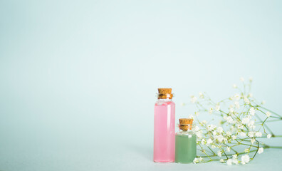 Bottles with cosmetics, gypsophila sprigs on blue background. Image with selective focus