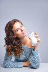 happy young woman drinking milk over grey background