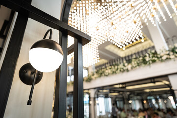 A pillar electric lighting lamp during glowing on in warm light shade with blurred background of luxury decoration lobby of the place. Interior equipment object.