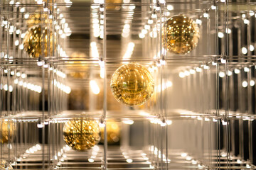 A shiny golden sphere ball and glowing light bulb with cubic wire cage, It is designed as lighting chandelier. Interior decoration object, background and texture photo.