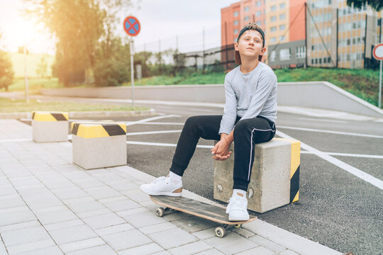 Teenager skateboarder boy portrait in a baseball cap with old skateboard on the city street. Youth generation Free time spending and an active people concept image.