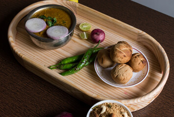 Traditional Rajasthani cuisine daal bati served on a wooden tray along with onion and daal bati churma