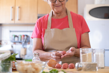 Smiling woman preparing meatballs in the home kitchen