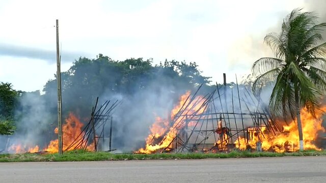 In bright flames burning indian hut made of wood and dried palm leaves of indigenous people in the tropical rainforest, district Waimiri Atroari, state of Amazon, Brazil.