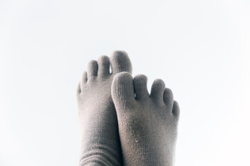 A couple of feet wearing finger socks, crossed, isolated on white background.