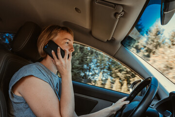 A young woman is using a mobile phone while driving a car