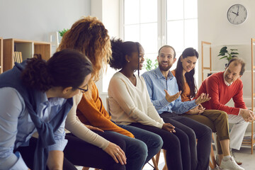 Interracial people sit in a row and communicate with each other sharing experiences. Corporate...