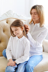 Mom straightens her daughter's hair. Parents and children. Famil