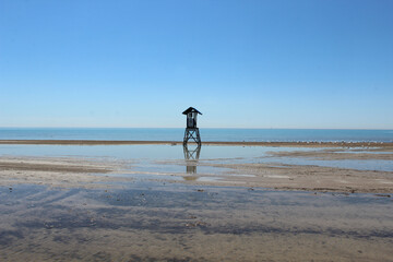 Flooded beach with stagnant water and lifeguard shack

