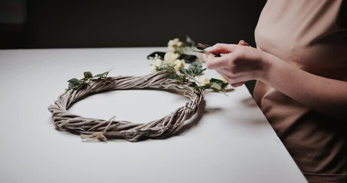 woman makes Easter decoration in the form of an Easter wreath with eggs and flowers