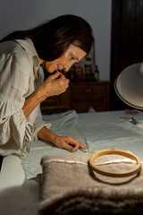 hispanic senior woman working with handmade fabrics in her home workshop - latinx